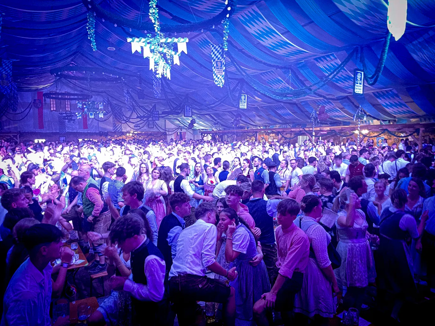 Volles Festzelt mit Publikum unter blauem Bühnenlicht