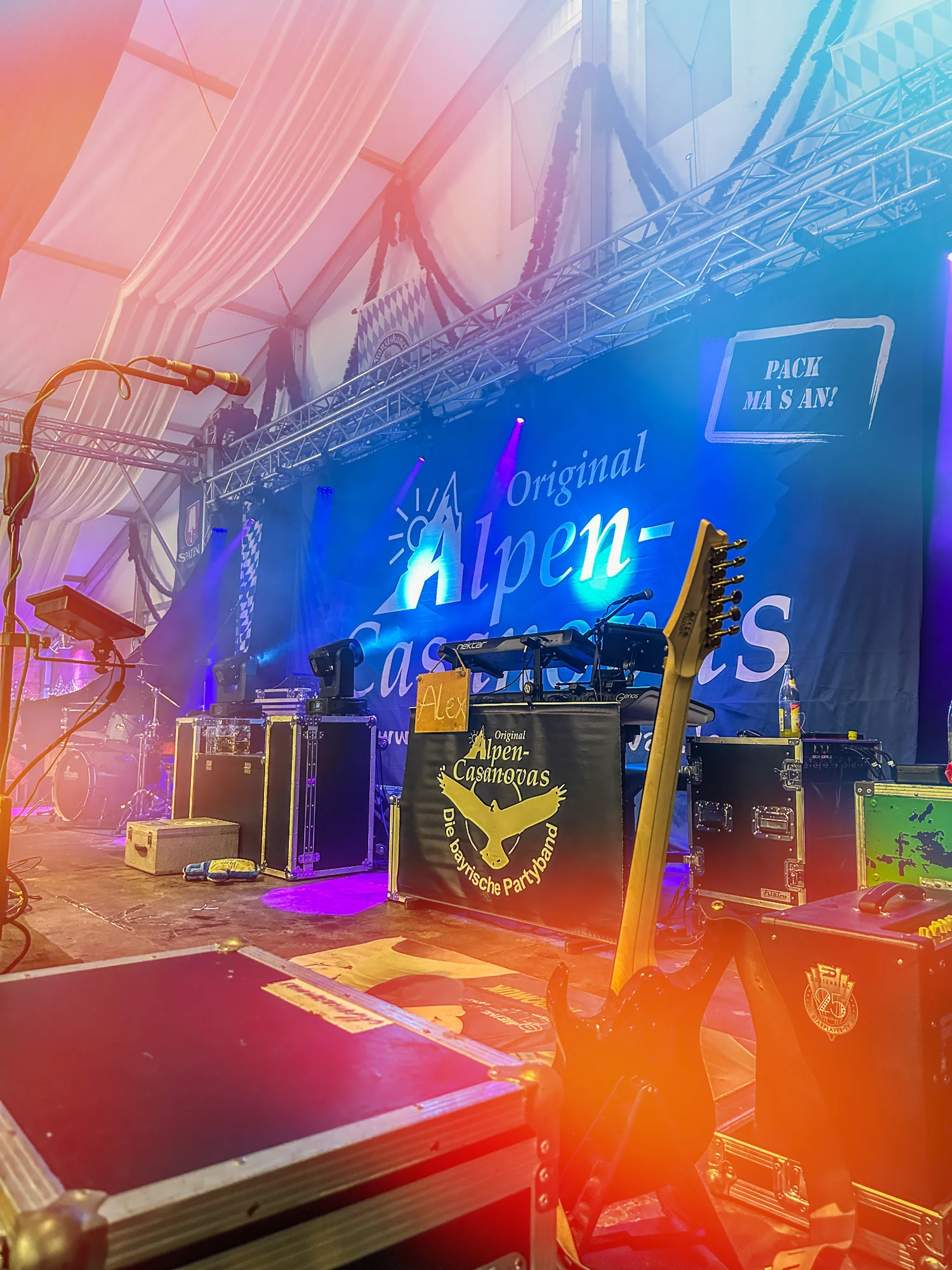 Bühne mit Gitarre und Branding der Original Alpencasanovas im Festzelt